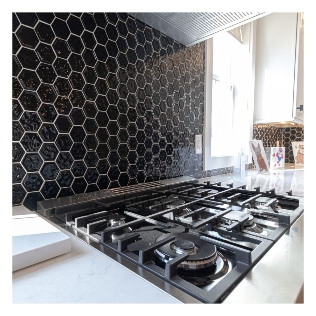 A new stove and black tile backsplash